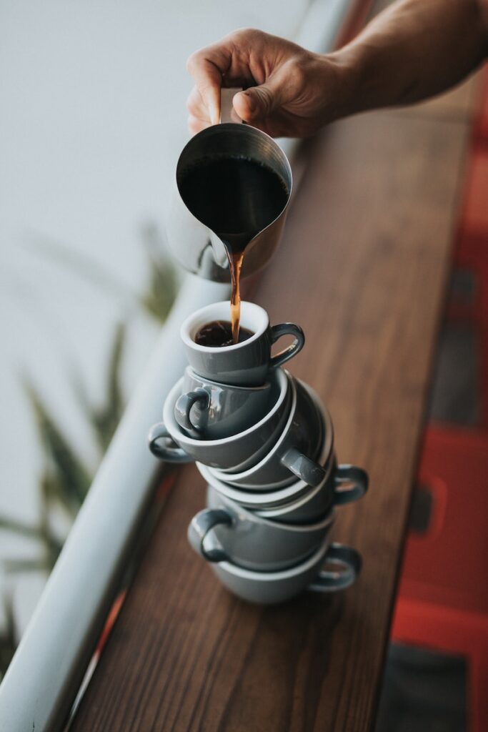 person holding gray stainless steel pitcher bside window