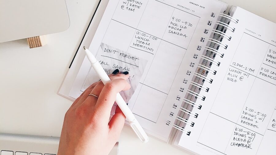 person holding notepad and pen flat lay photography