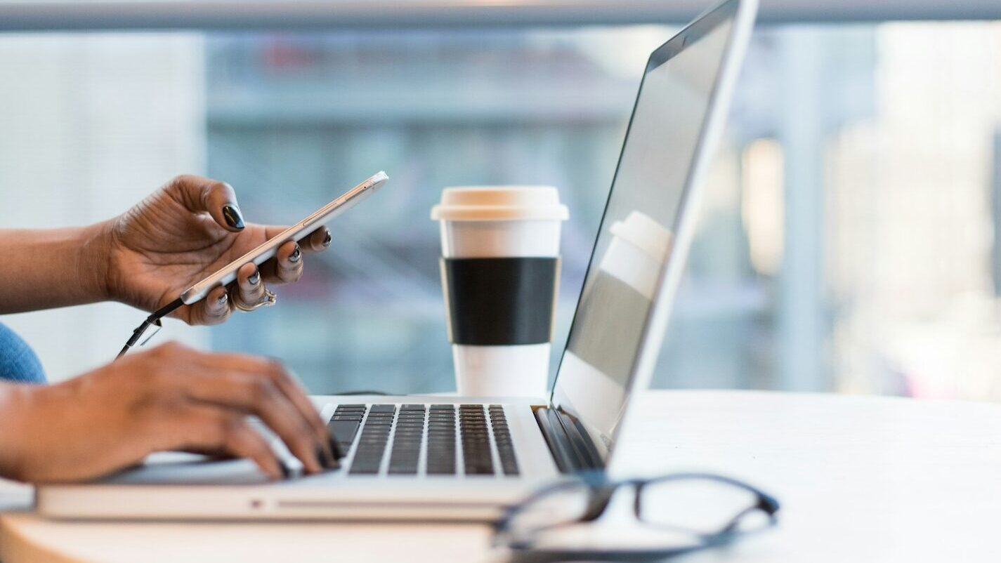 person using smartphone and MacBook